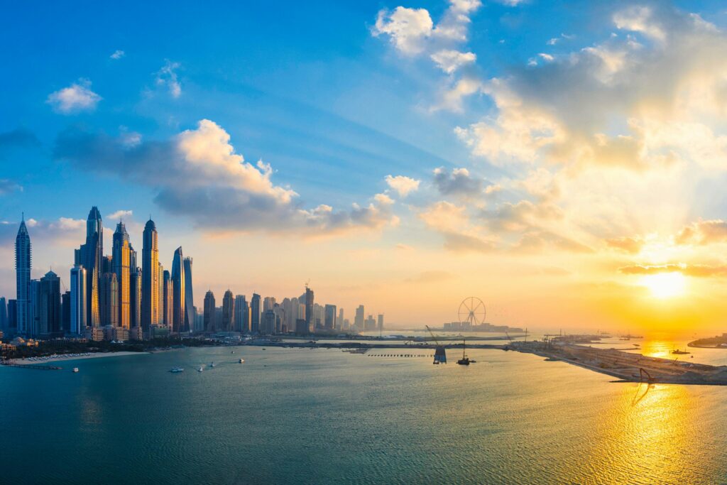 Stunning view of Dubai's skyline and waterfront during golden hour with glowing skyscrapers reflecting on the water.