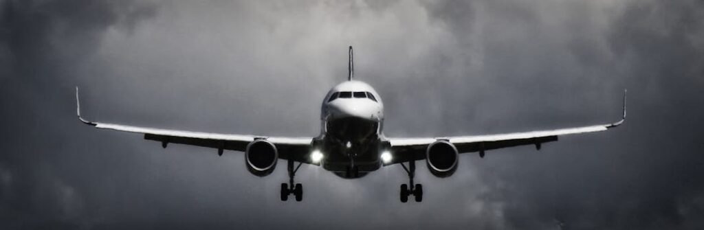 A dramatic view of an airplane landing with stormy clouds overhead, showcasing aviation in a monochrome scene.