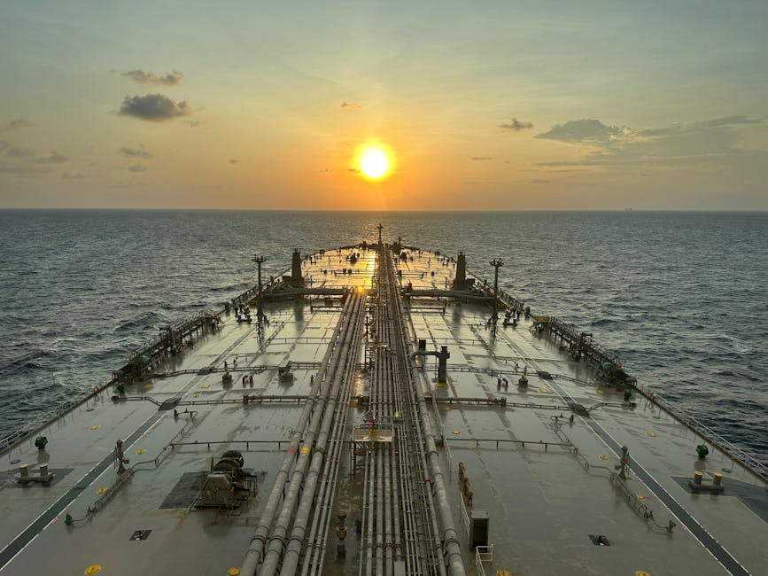 A large oil tanker sailing on the ocean with a sunset view.